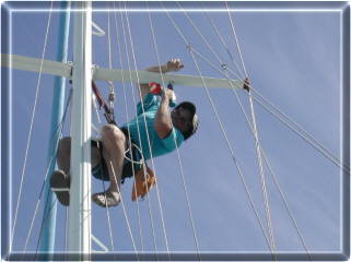 Tertius half way up the mast fitting pulleys under the spreaders to hoist courtesy flags